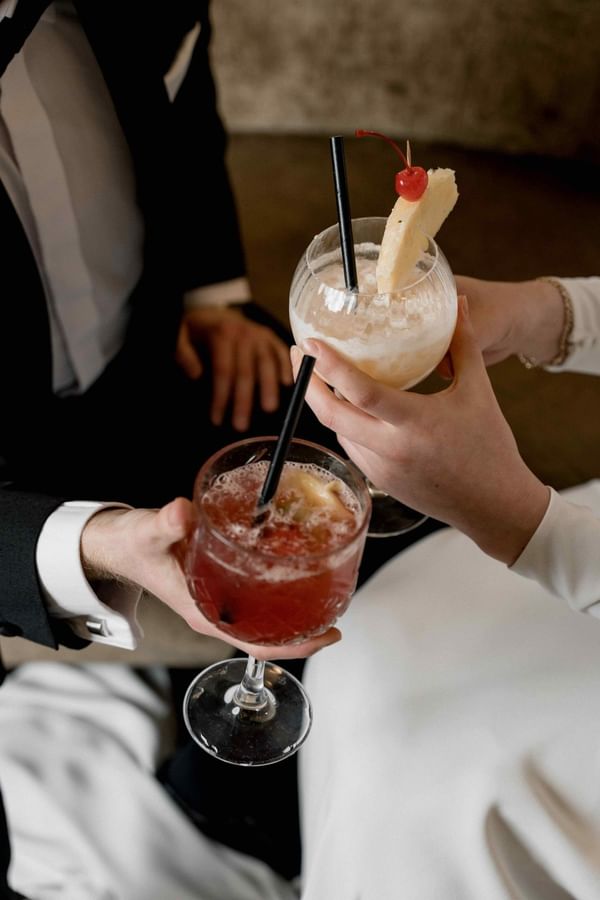 Couple holding cocktails with straws and garnishes at Barsey by Warwick 