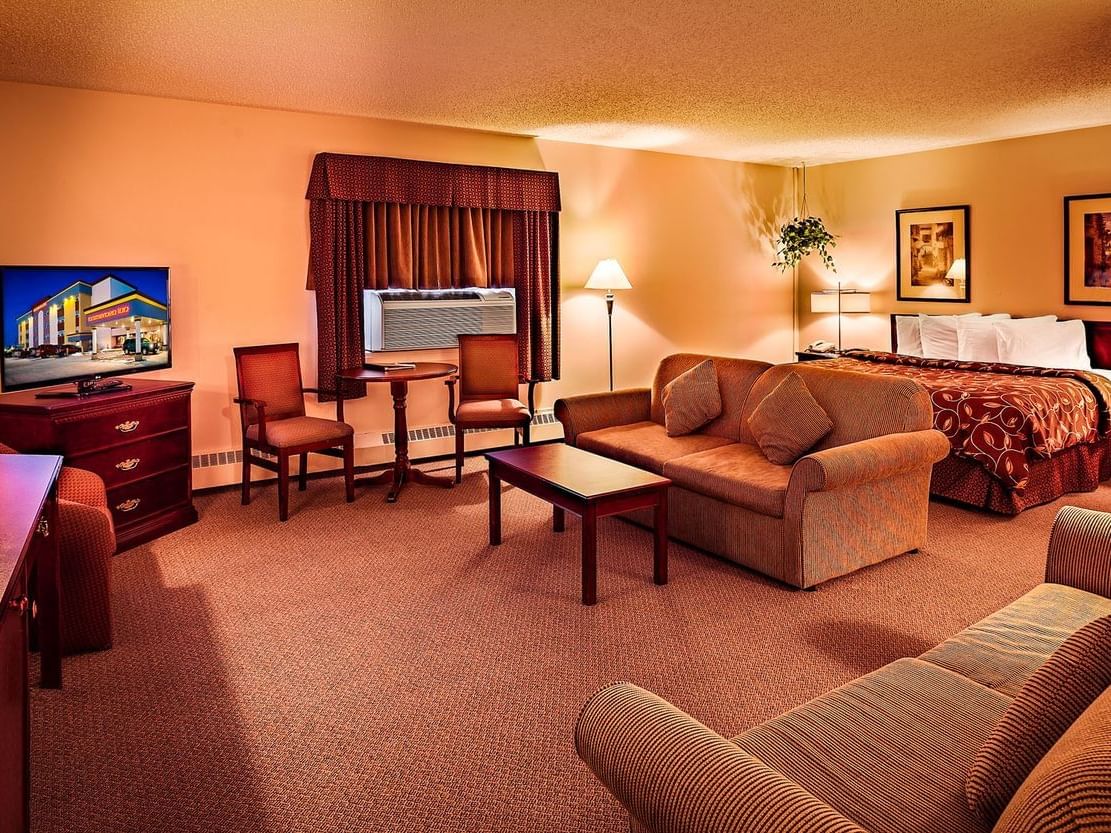 room with bed, sofa, dining table and television on dresser