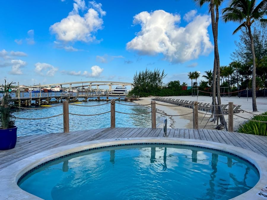 Jacuzzi Blue hot tub by a wooden deck overlooking a harbor and bridge under a cloudy sky at Warwick Paradise Island Bahamas