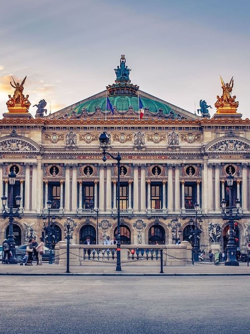 The Palais Garnier by gold statues under a green dome near a stone plaza near Warwick Paris Champs Elysées