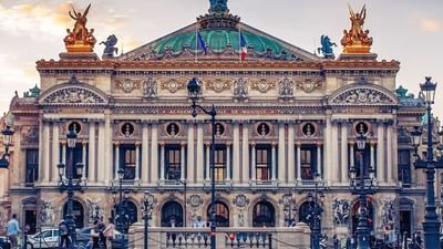 The Palais Garnier by gold statues under a green dome near a stone plaza near Warwick Paris Champs Elysées