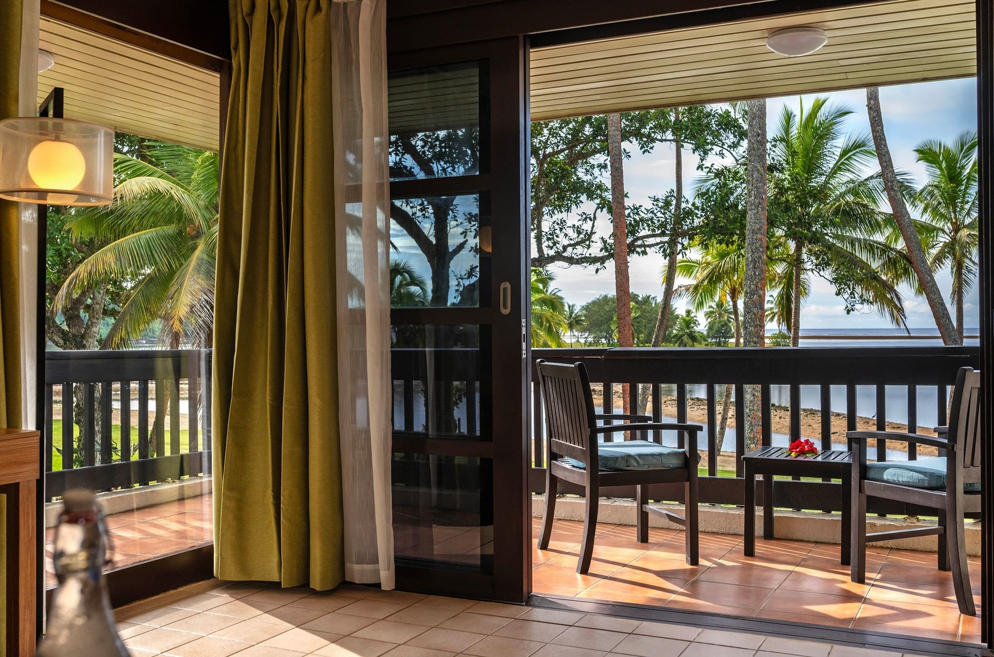 Two chairs and a small table on a balcony with ocean view at Naviti Resort Fiji Coral Coast