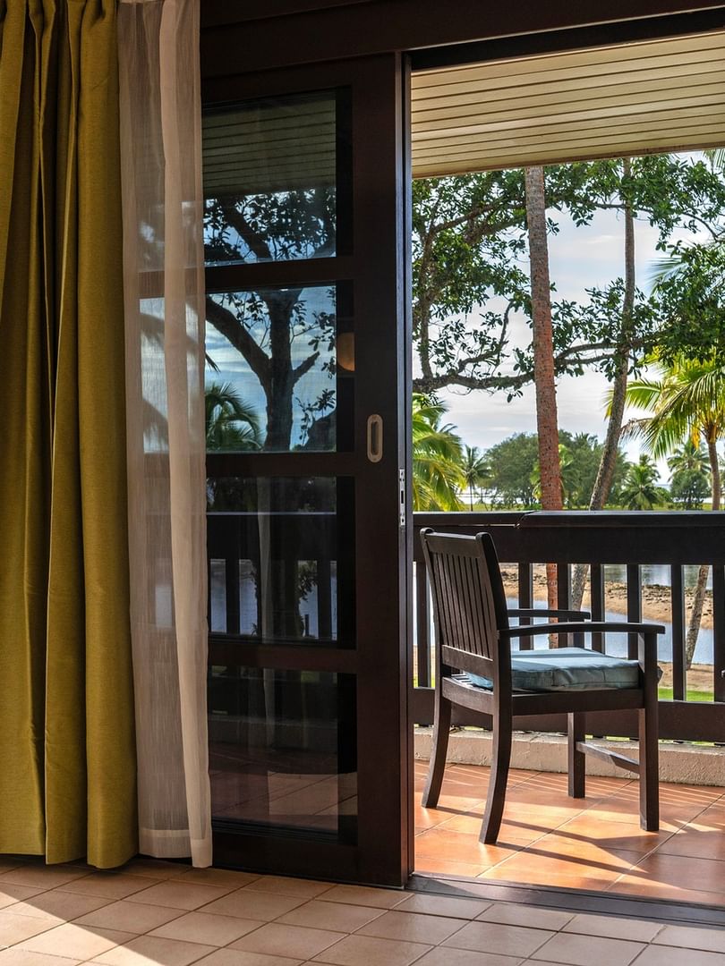 Wooden chairs on a tiled balcony by a sliding glass door in suites at The Naviti Resort in Korolevu.