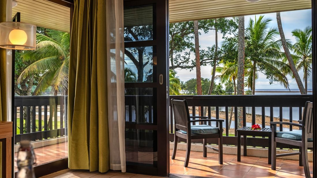 Wooden chairs on a tiled balcony by a sliding glass door in suites at The Naviti Resort in Korolevu.