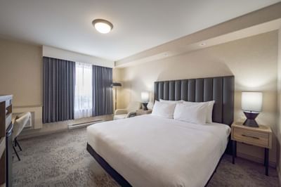 Modern hotel room with large bed, patterned carpet and closed curtains at Sandman Hotel & Suites Winnipeg Airport