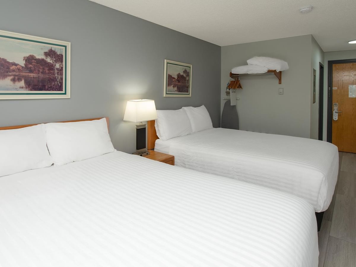 Coast Two Queens with Kitchenette featuring two queen beds, gray walls, and wood-style flooring.