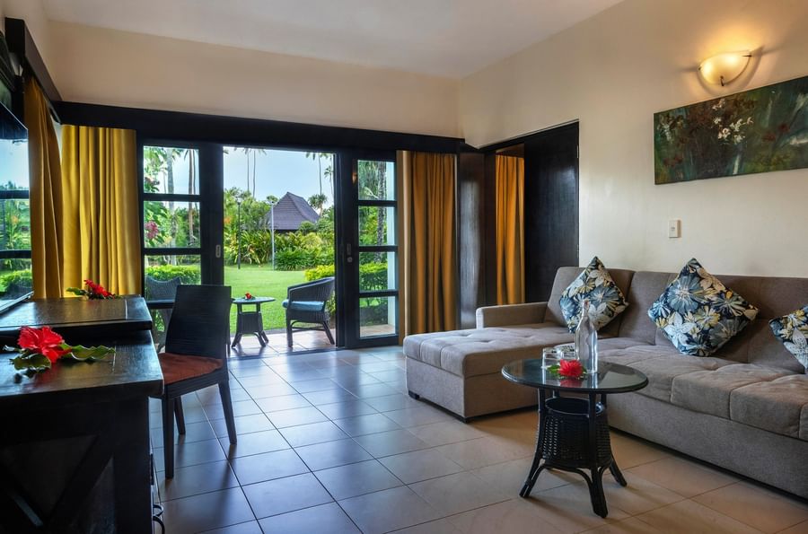 Living room with couch, table, and patio doors leading to balcony at The Naviti Resort - Fiji.