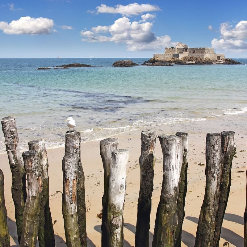 Sandy beach with wooden posts emerging from the waves featuring Saint Malo Beach near Warwick Hotels and Resorts