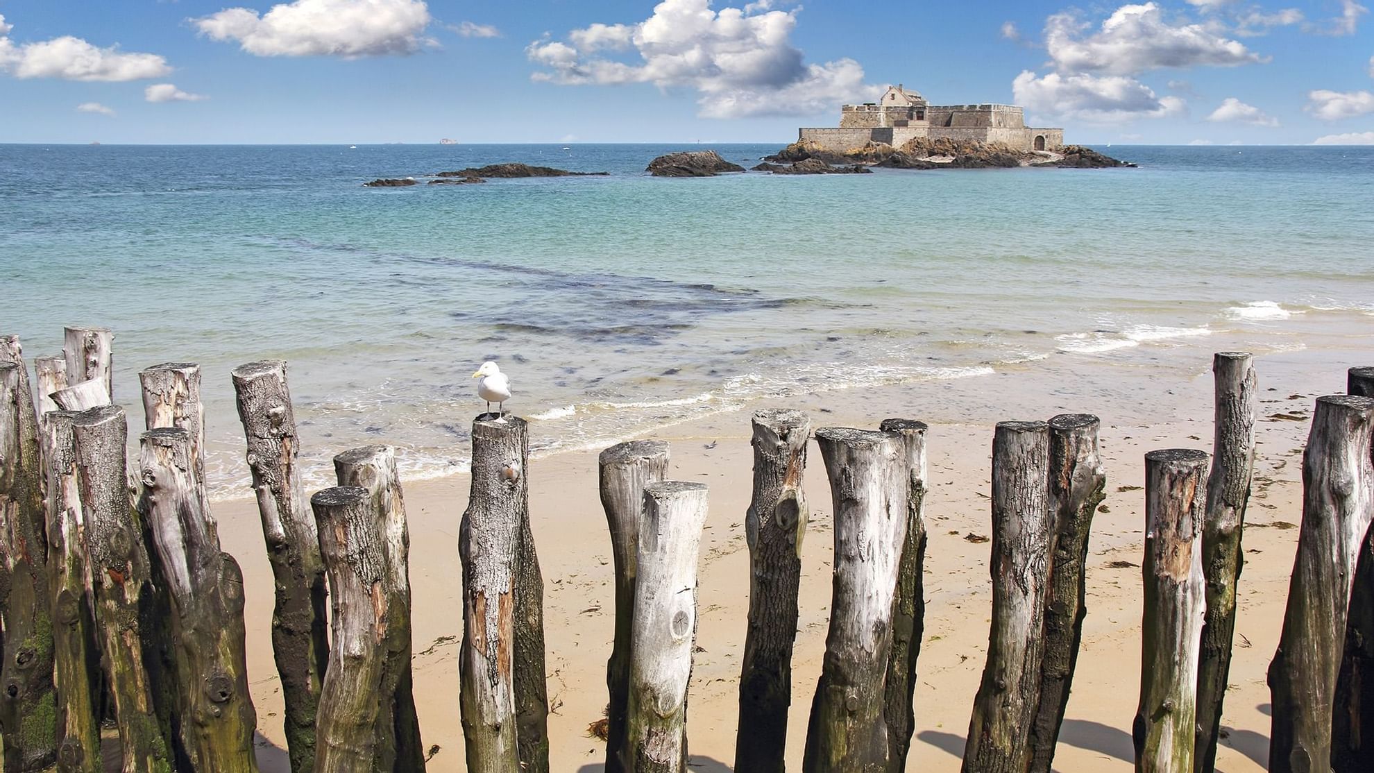 Sandy beach with wooden posts emerging from the waves featuring Saint Malo Beach near Warwick Hotels and Resorts