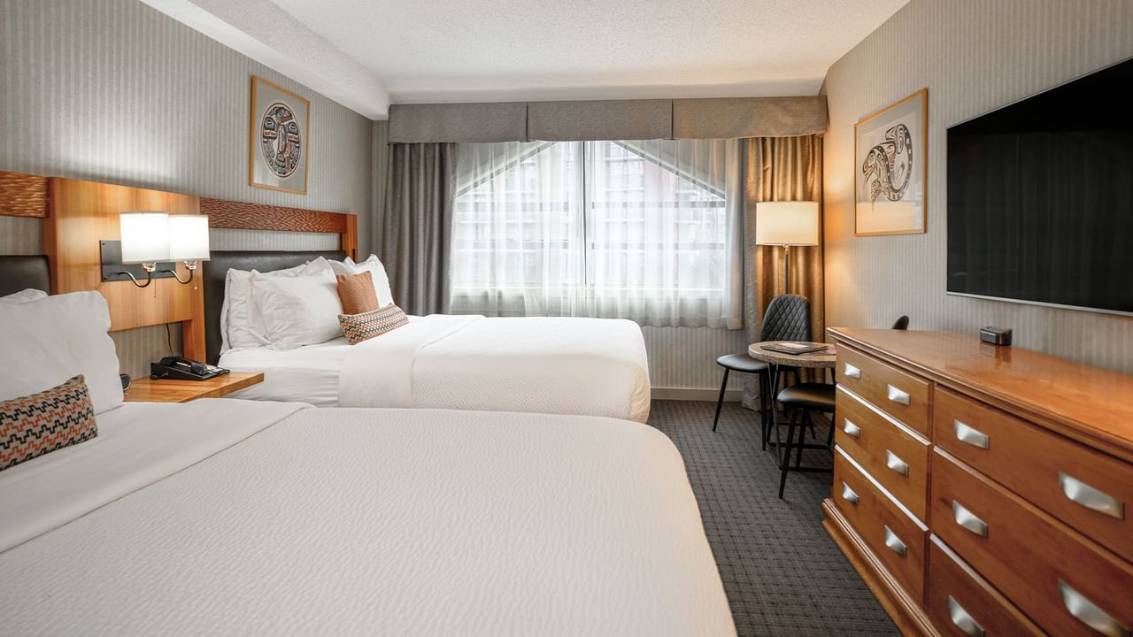 Spacious hotel room with two queen beds, elegant decor and HDTV.