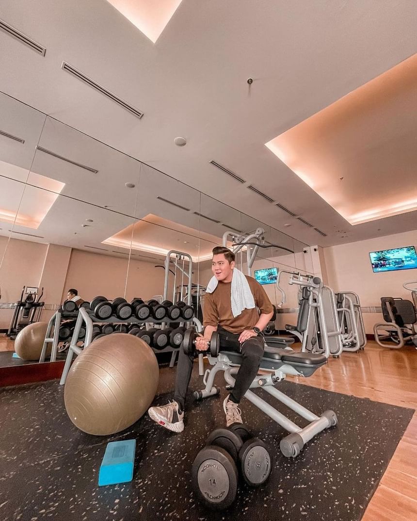 Man sitting on a machine with weights in the Gym at Po Hotel Semarang