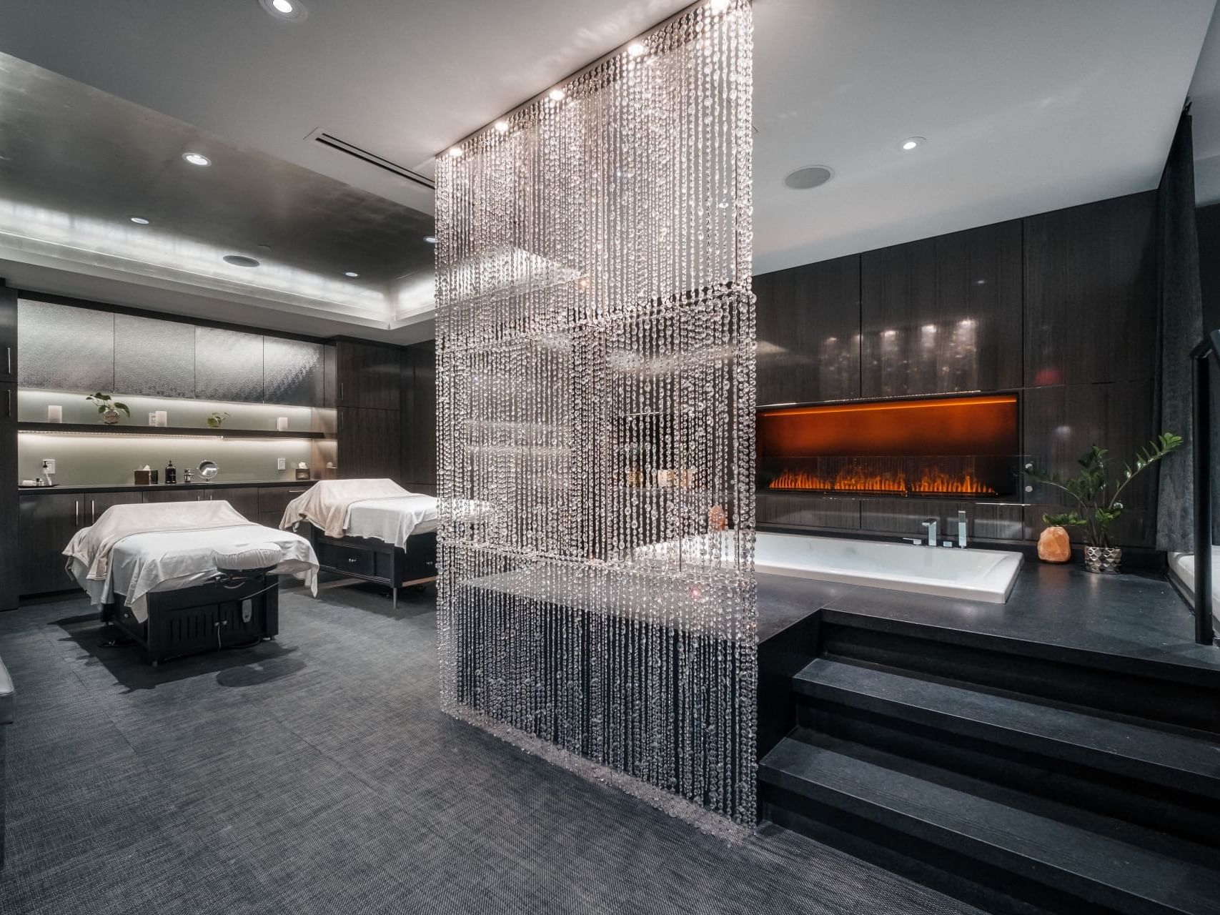 Luxurious dark spa treatment room for couples with jacuzzi and day bed
