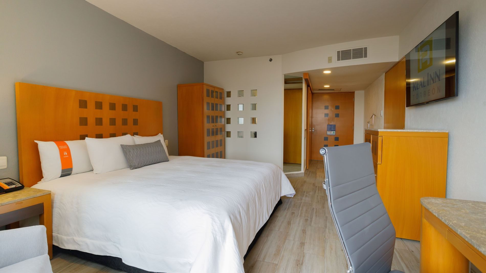1 Double Deluxe Handicap Accessible room showing a plush king bed, wood accents, and a wall-mounted TV at Real Inn Torreon