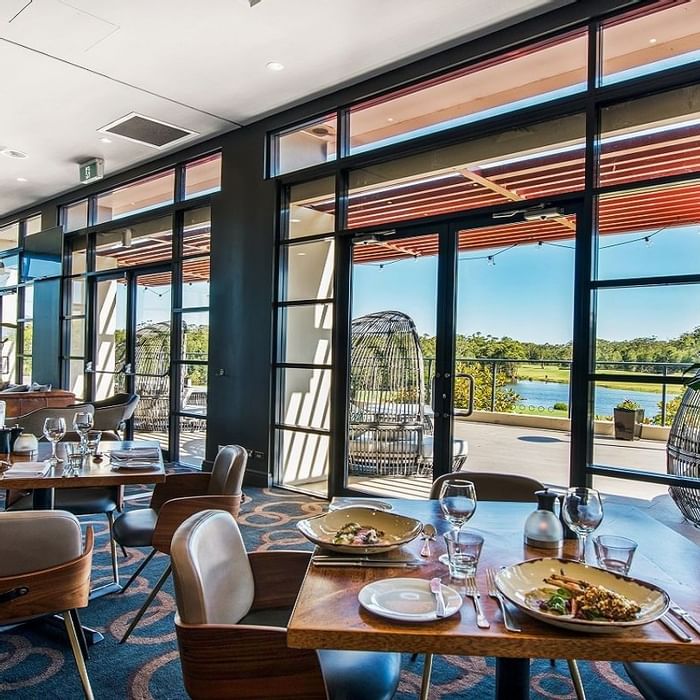 Karinyas Restaurant interior with natural light, overlooking a serene waterfront at Mercure Kooindah Waters