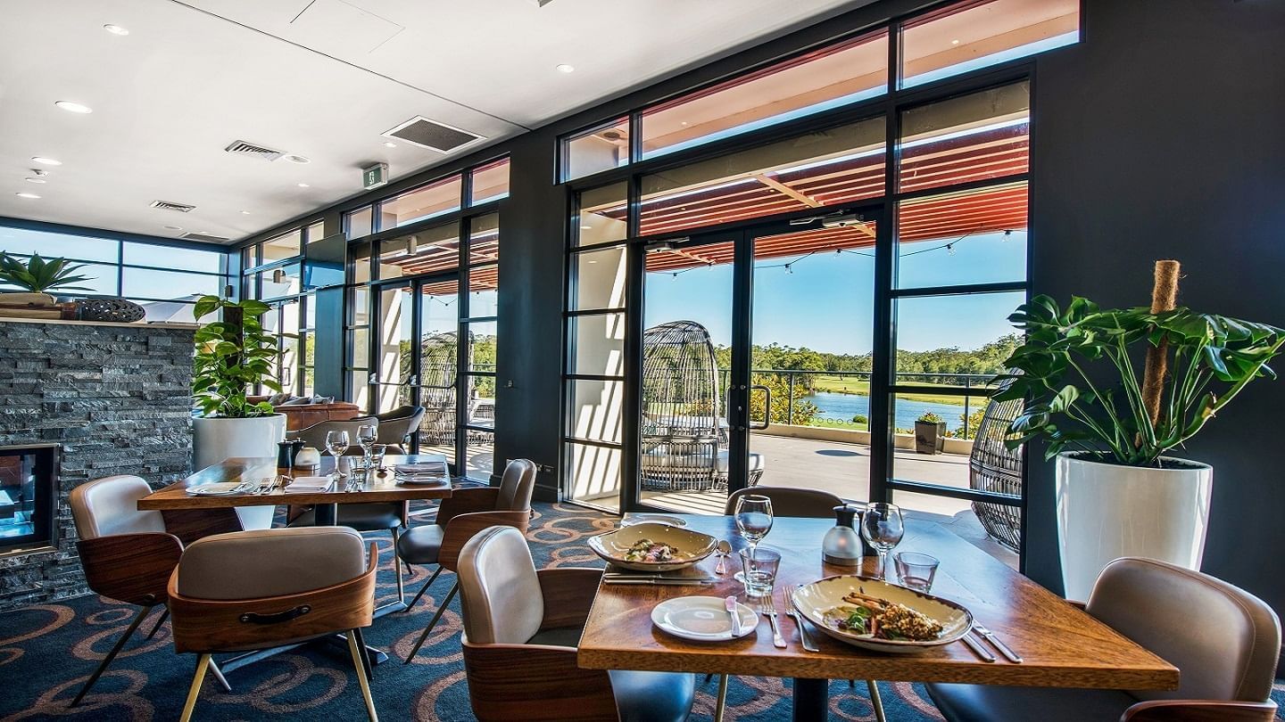 Karinyas Restaurant interior with natural light, overlooking a serene waterfront at Mercure Kooindah Waters