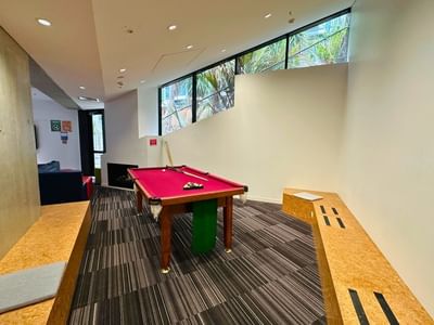 A billiard table with cue sticks and balls in a lounge area at UniLodge Auckland City.