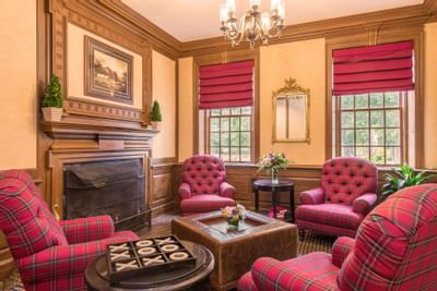 Cozy sitting area at The Exeter Inn with a fireplace and red plaid armchairs, perfect for relaxing