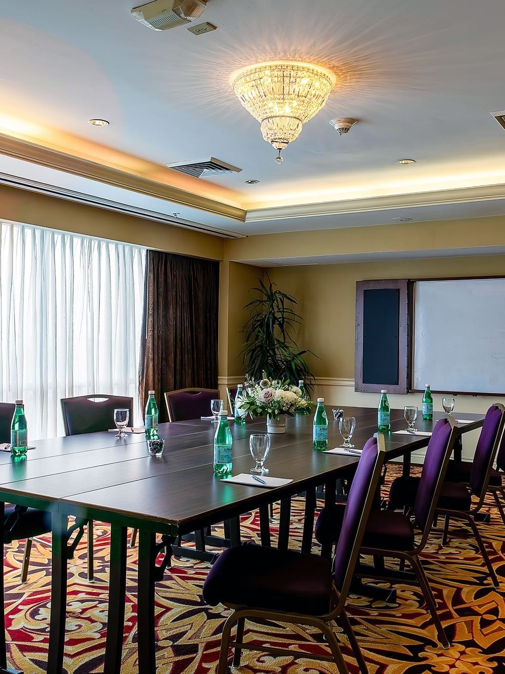 Cambridge at Warwick Denver with water bottles on a long table by purple chairs under a chandelier