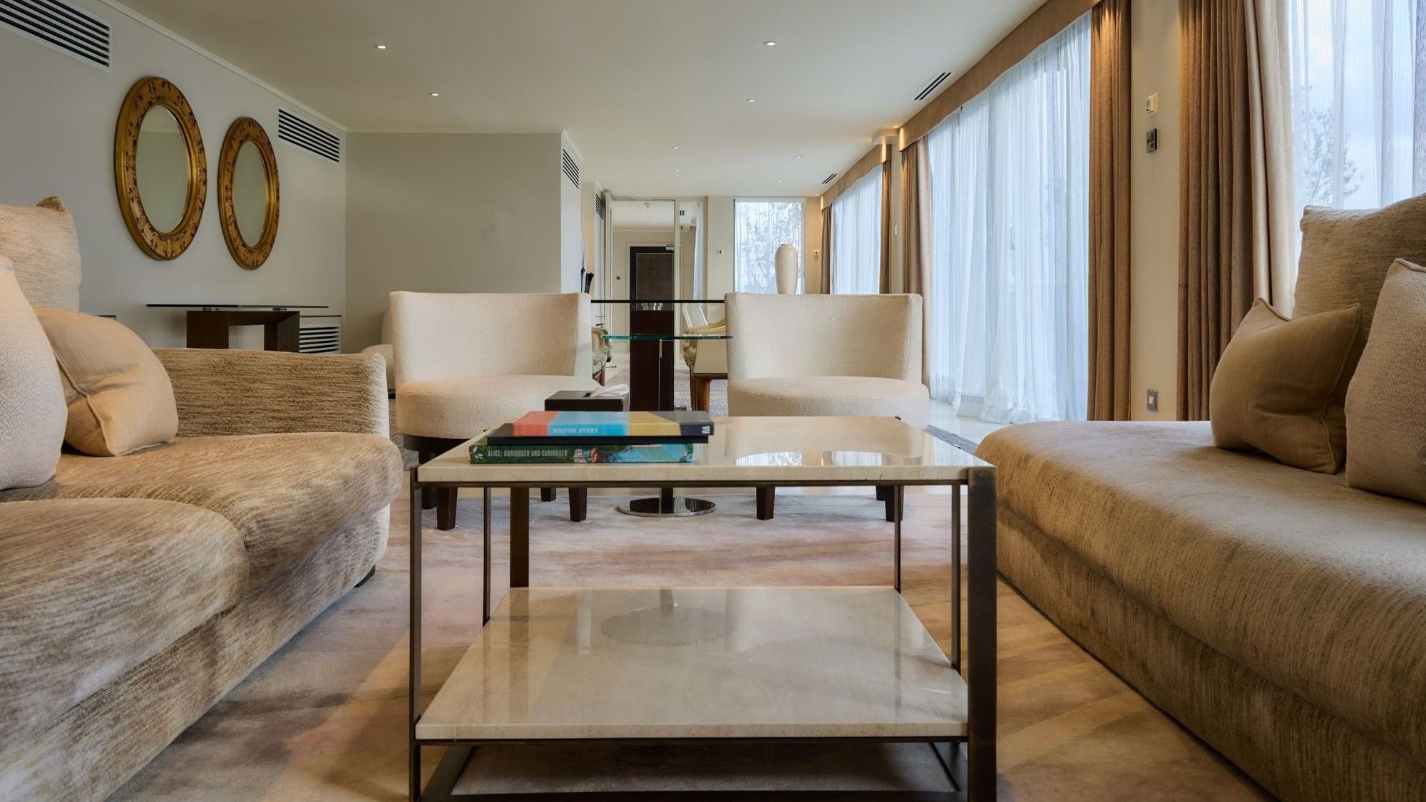 Spacious living area with plush sofas, coffee table and floor-to-ceiling windows to the terrace at The May Fair Hotel, London.