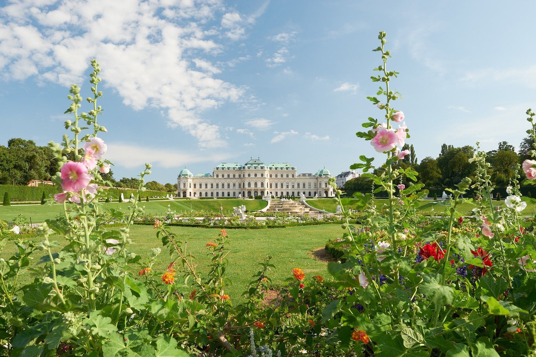 Schloss Belvedere in Wien mit barocker Gartenanlage und blühenden Blumen im Vordergrund.