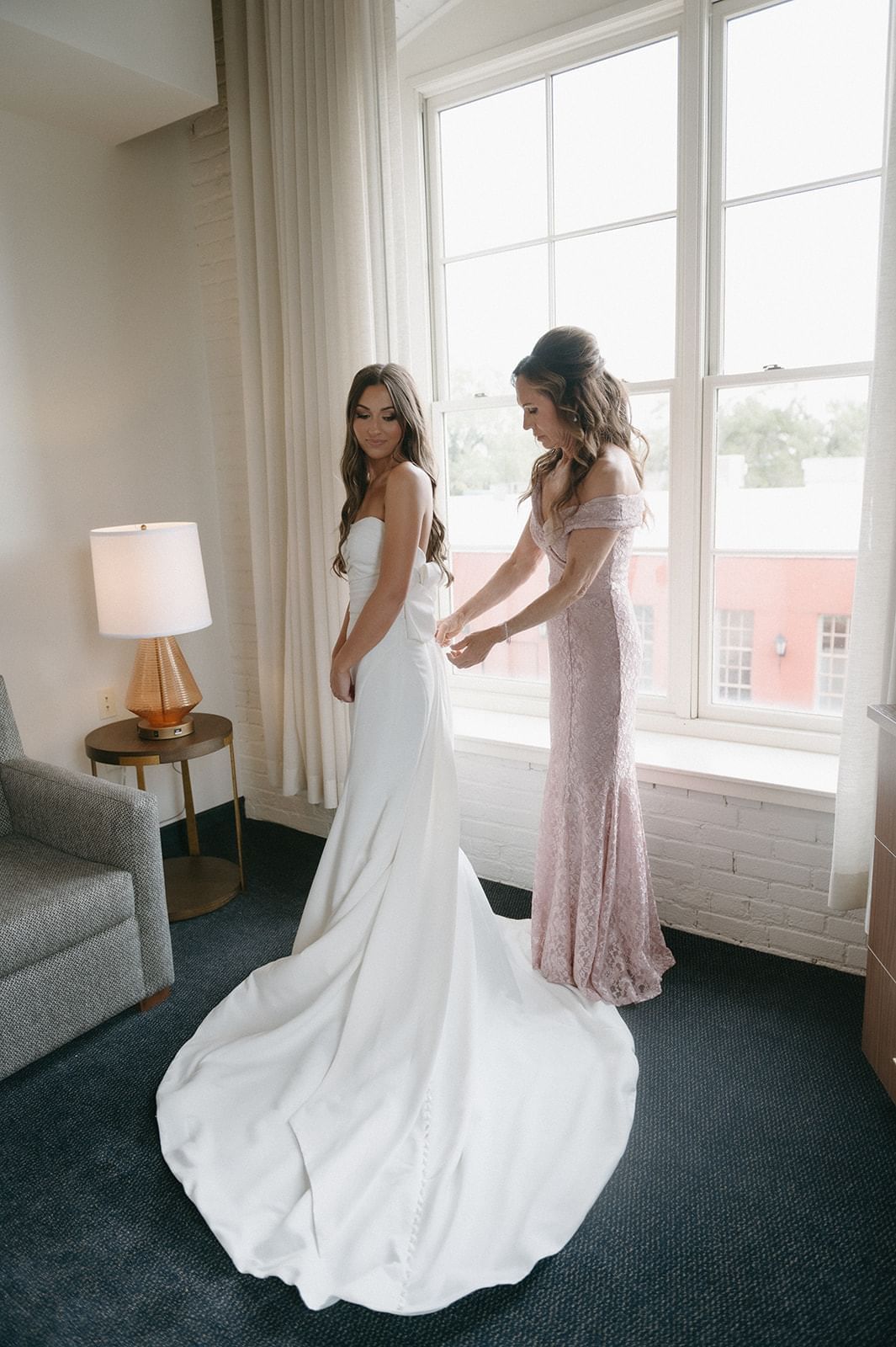 Two women in formal dresses standing in a hotel room