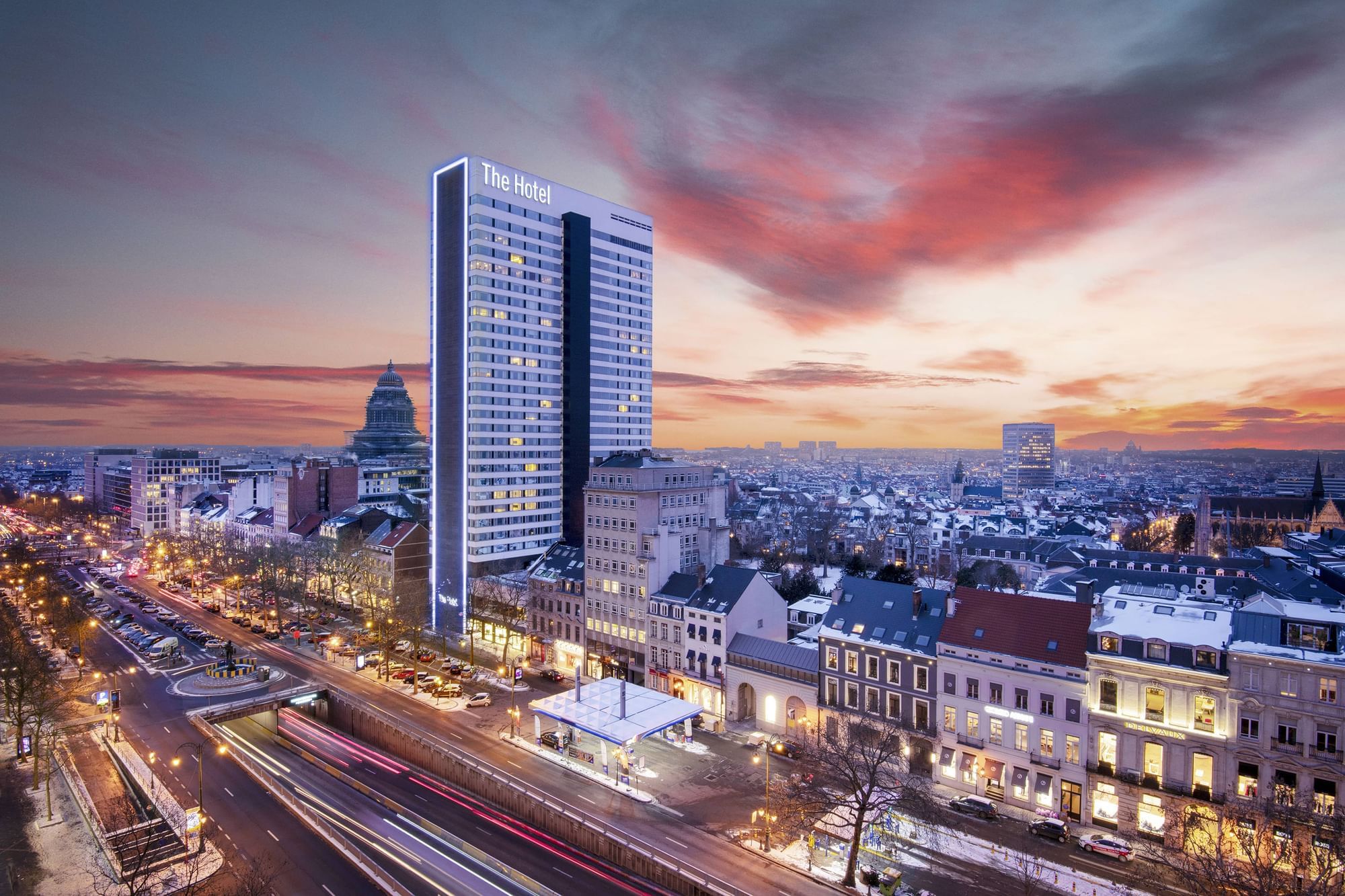 Aerial night view of the city with busy streets & the hotel exterior of The Hotel Brussels