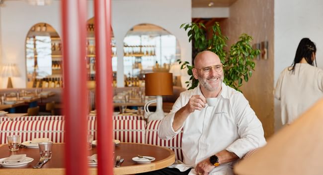 Cibaria Manly at Elysium Manly featuring a smiling man sitting at a striped booth table enjoying a hot drink