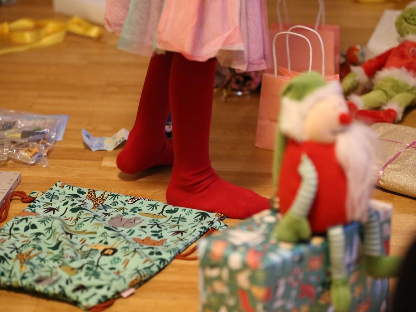 Child standing in red tights near gifts, holiday decorations, and elf plush toys at Shangri-La Resort and Golf Club