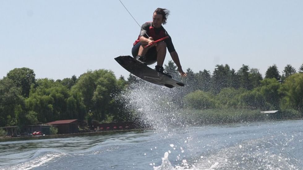 Man wearing a red swimsuit skiing on the water with a waterskiing board near Falkensteiner Hotel Belgrade