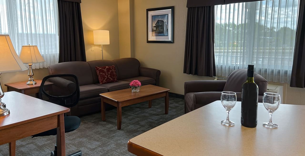 Living area of hotel suite with sofa, table, and wine