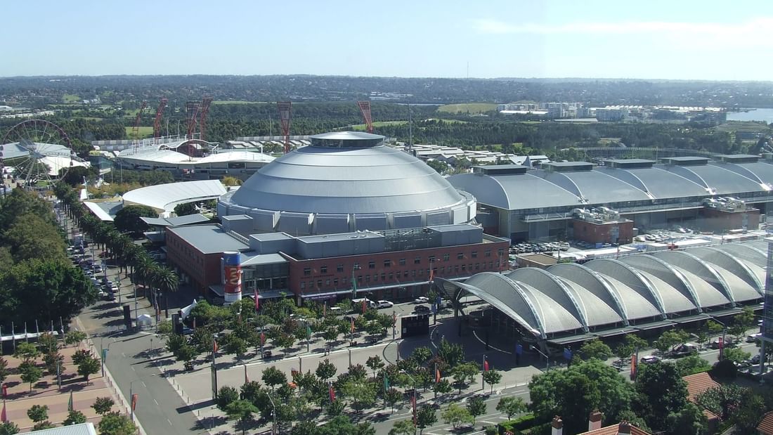 Aerial view of Sydney Showground surrounded by modern buildings and green spaces near Novotel Sydney Olympic Park