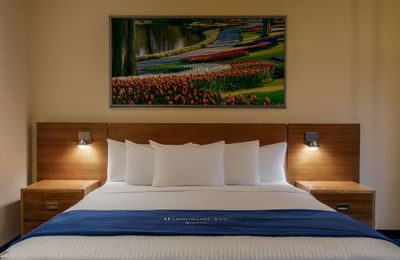 Queen bed & wall lamps with art in Suite at Harborside Inn