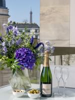 Champagne and flowers on a glass table by white chairs in The Montaigne Suite at Warwick Paris Champs Elysées