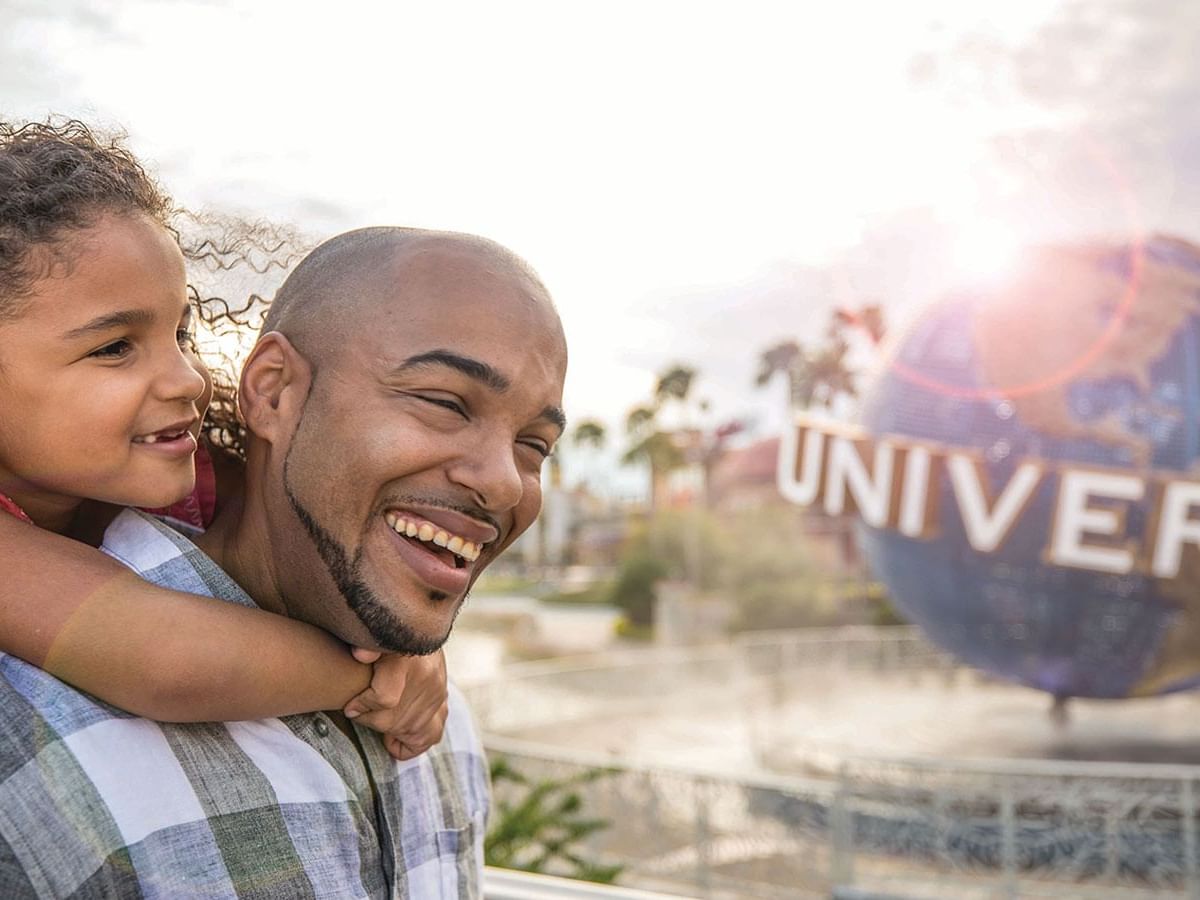 Father and daughter embracing in front of the Universal Studios globe near Rosen Inn Universal