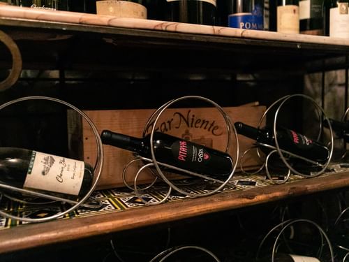 Estante en una bodega con botellas de vino en soportes metálicos en La Cava de Santiago en Hacienda del Mar Los Cabos