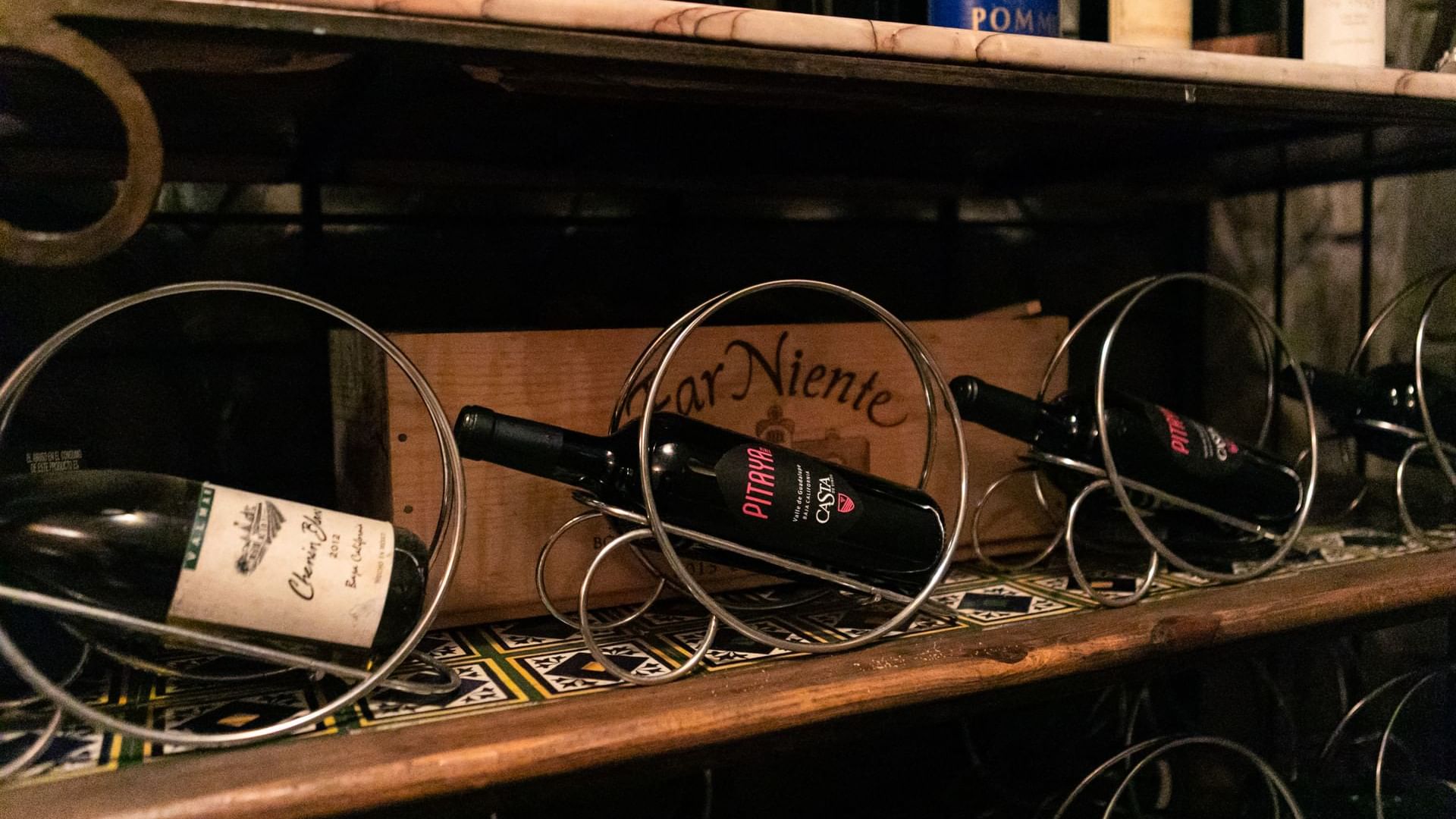 Estante en una bodega con botellas de vino en soportes metálicos en La Cava de Santiago en Hacienda del Mar Los Cabos