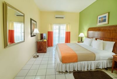 Bright hotel room featuring a king-sized bed, colorful walls, a large mirror in Standard Room King at Bay Gardens Inn