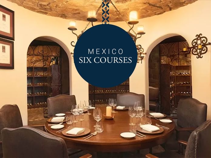 Set dining table with wine glasses and plates in a restaurant with Mexico Six Courses offer at Hacienda del Mar Los Cabos.