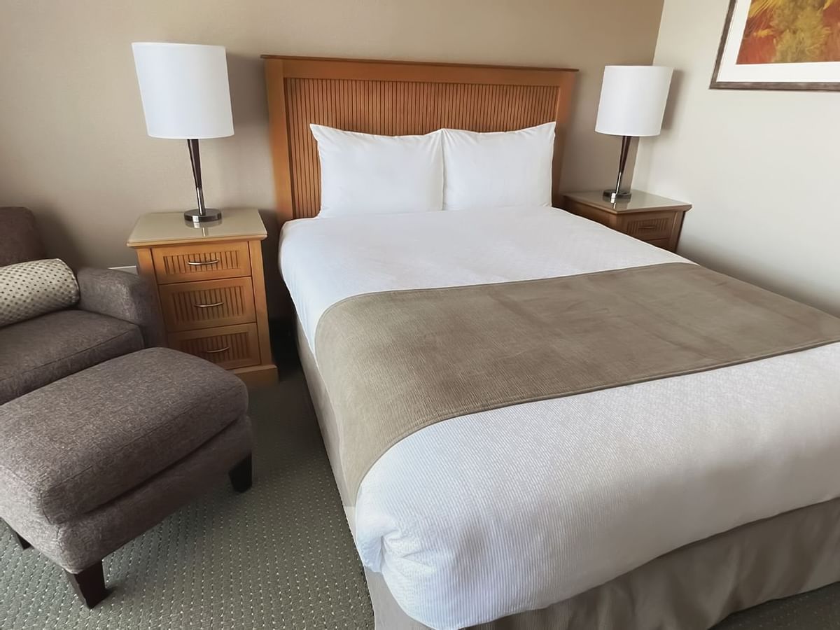guest room with queen bed, chair and lamps