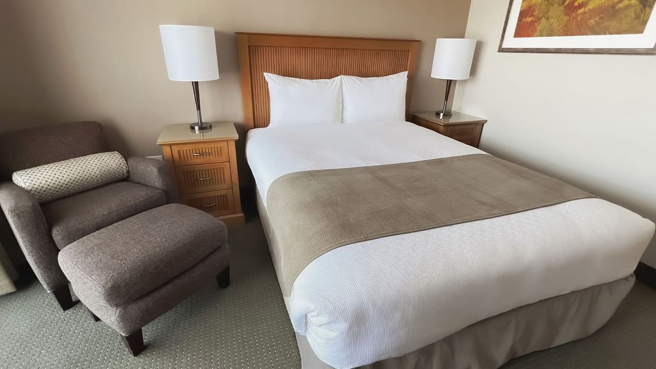 guest room with queen bed, chair and lamps
