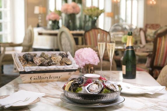 Table setting with a plate of fresh oysters, a basket of oysters, & champagne flutes in Park Lounge at Park Hyatt Saigon