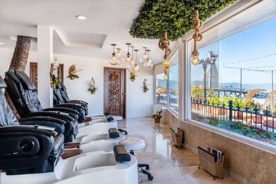 Spa pedicure area with massage chairs, pendant lighting, and ocean views at Playa Los Arcos Puerto Vallarta 2023