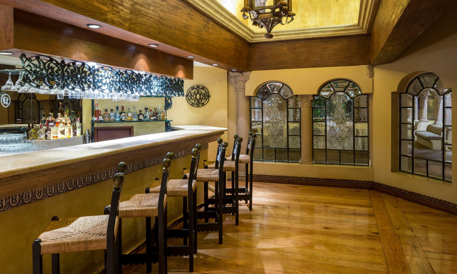Los Murales restaurant with a stylish wood-paneled bar with woven stools and leaded windows at Quinta Real Aguascalientes