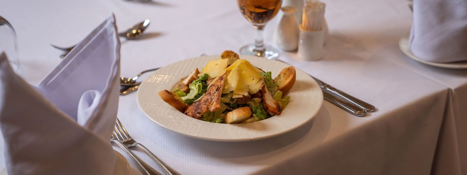 Chicken Caesar salad and shaved parmesan cheese on white plate in AI Firdous restaurant at Saja Warwick Madinah