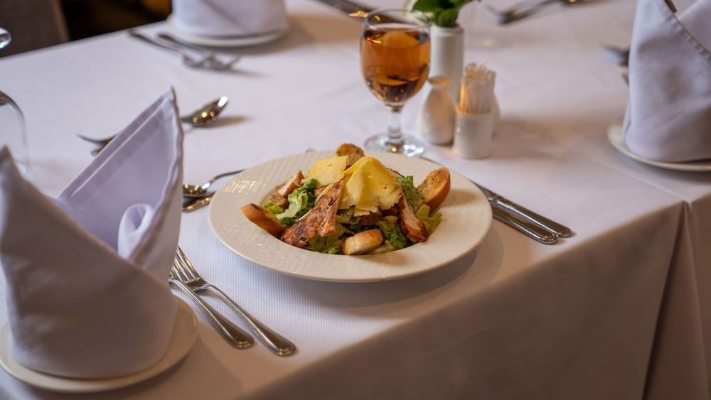 Chicken Caesar salad and shaved parmesan cheese on white plate in AI Firdous restaurant at Saja Warwick Madinah