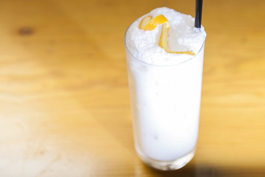 white drink in tall glass on a bar