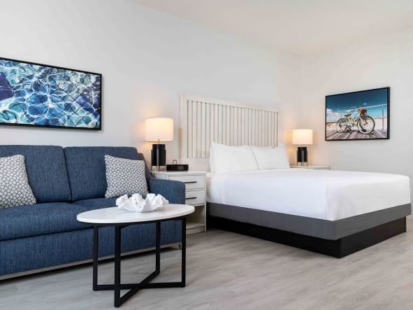 Hotel guest room with white bedding and blue couch  