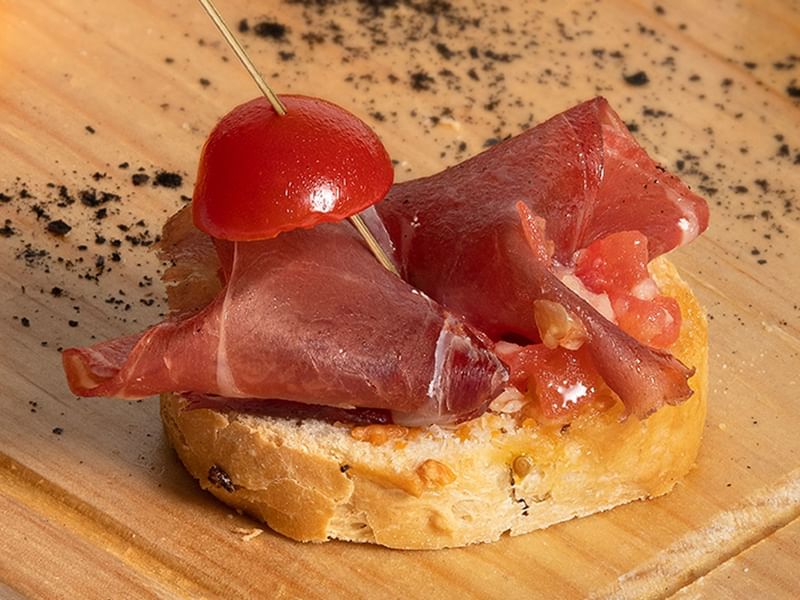 Tapas-style bread with cured ham and a cherry on top in Stelaris Cocktail Lounge at Grand Fiesta Americana