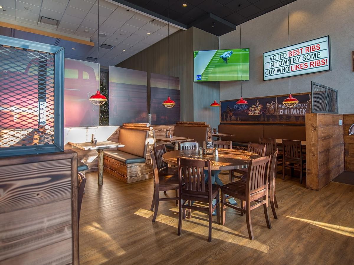 Montana's BBQ & Bar dining area with tables, chairs, and TV playing sport.