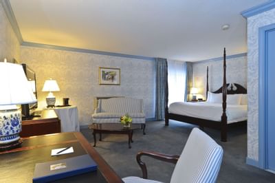 Work desk and striped sofa in front of four-poster bed in guest suite at Farmington Inn and Suites